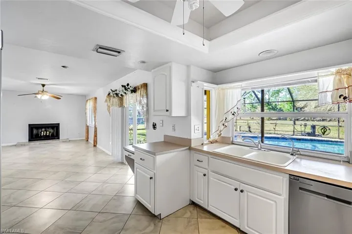 Kitchen with a ceiling fan, white cabinetry, dishwasher, and light countertops