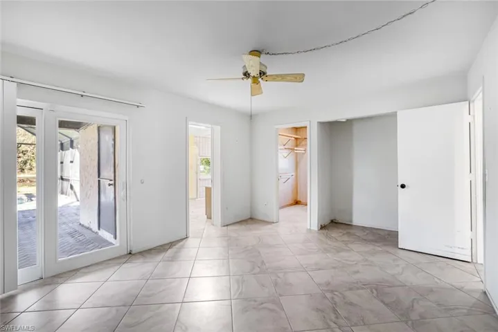 Unfurnished bedroom featuring ceiling fan, a walk in closet, and access to outside