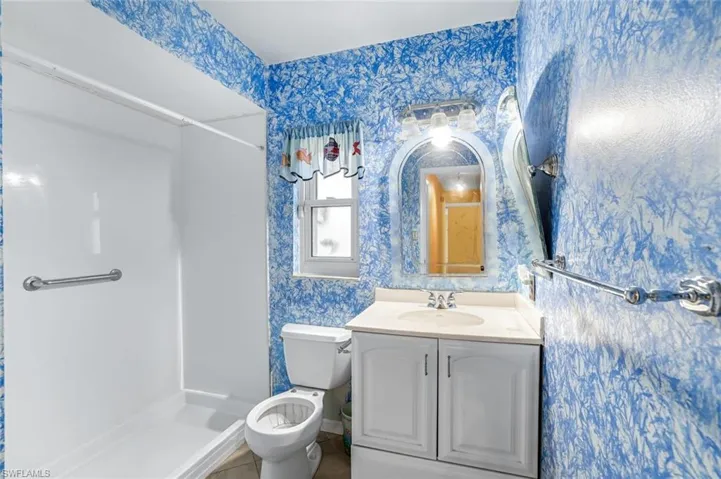 Full bath with vanity, a stall shower, and wallpapered walls