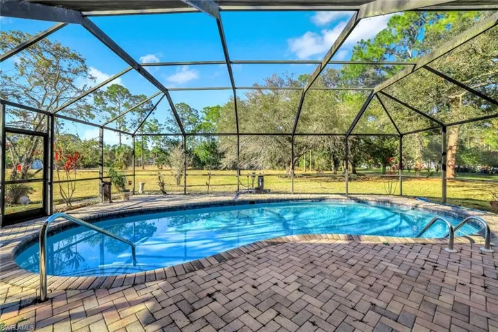 Outdoor pool with a sunroom, glass enclosure, a lawn, and a patio