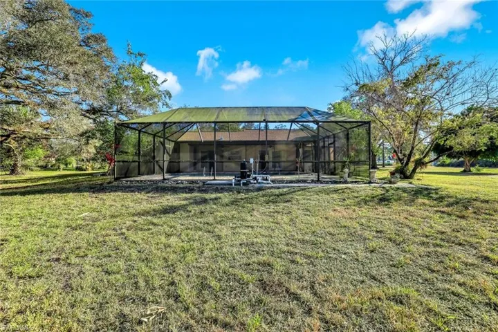 View of grassy yard with a lanai and a sunroom