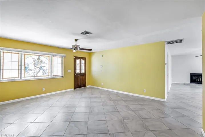 Foyer featuring a ceiling fan and a fireplace with raised hearth