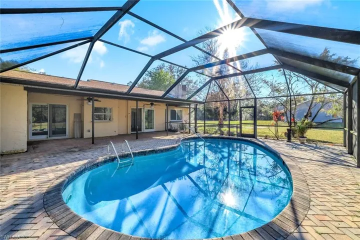 Swimming pool featuring a sunroom, a patio area, and glass enclosure