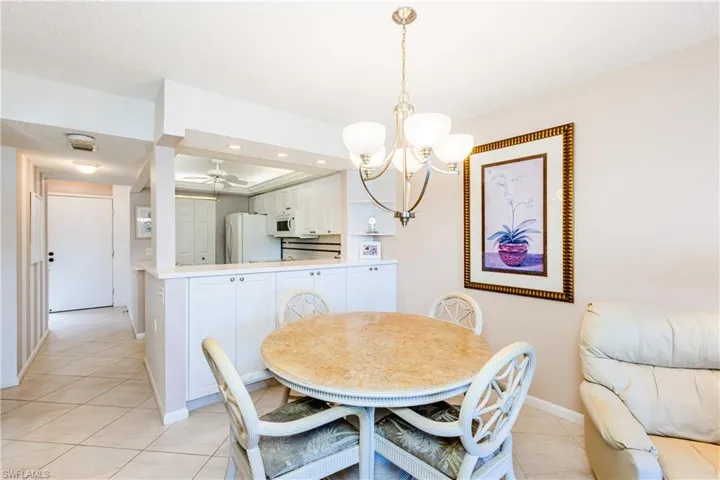 Tiled dining area featuring ceiling fan with notable chandelier, a tray ceiling, and a textured ceiling