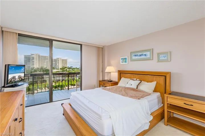 Bedroom featuring a wall of windows, light colored carpet, and access to outside