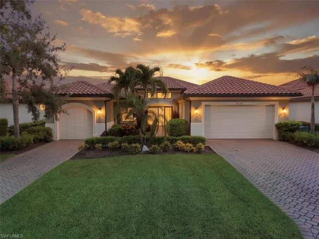 Mediterranean-style residence featuring a tile roof, dual garage doors, and a paver driveway