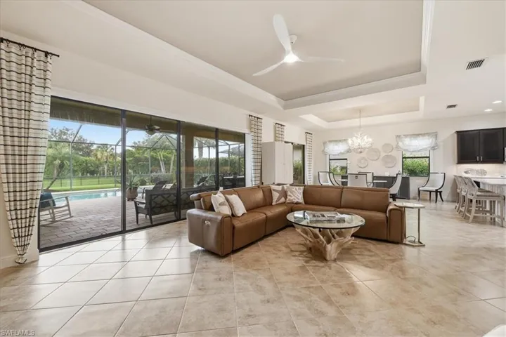 Large format tile flooring, tray ceilings, recessed lighting, and a modern ceiling fan