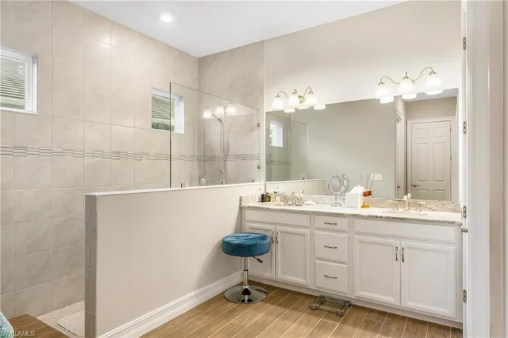 Bathroom featuring double vanity, a walk in shower, and wood tiled floors