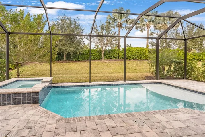 View of swimming pool with a sunroom, glass enclosure, a pool with connected hot tub, a yard, and a patio area