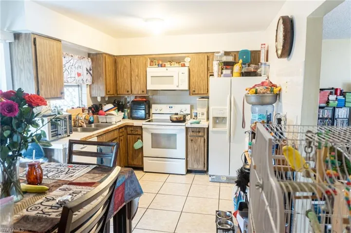 Kitchen with white appliances, wood finish cabinets, light countertops, and light tile patterned flooring