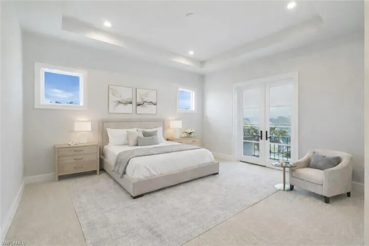Bedroom featuring french doors, access to outside, light carpet, a tray ceiling, and recessed lighting
