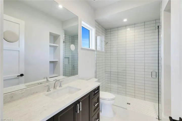 Bathroom featuring a shower stall, vanity, built in shelves, and recessed lighting