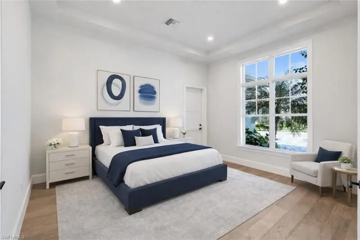 Bedroom with a tray ceiling, light wood-type flooring, and recessed lighting