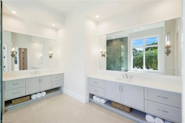 Full bathroom featuring a marble finish shower, two vanities, and recessed lighting