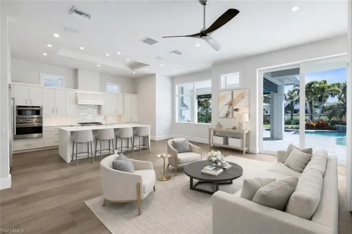Living room featuring ceiling fan, light wood-type flooring, healthy amount of natural light, recessed lighting, and a raised ceiling