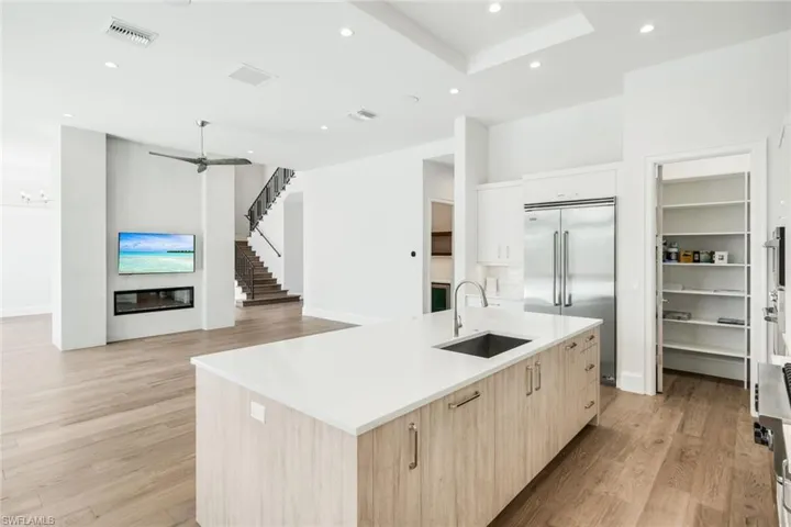 Two tone kitchen with a kitchen island with sink, light wood-type flooring, stainless steel appliances, modern cabinets, and recessed lighting