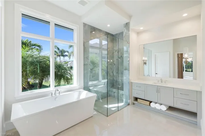 Full bath featuring a marble finish shower, vanity, a soaking tub, and light tile patterned floors