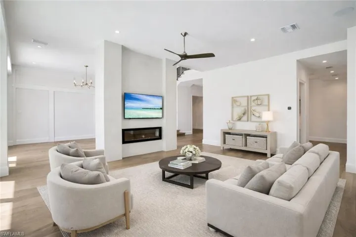 Living area with a glass covered fireplace, light wood-style floors, ceiling fan, and a chandelier