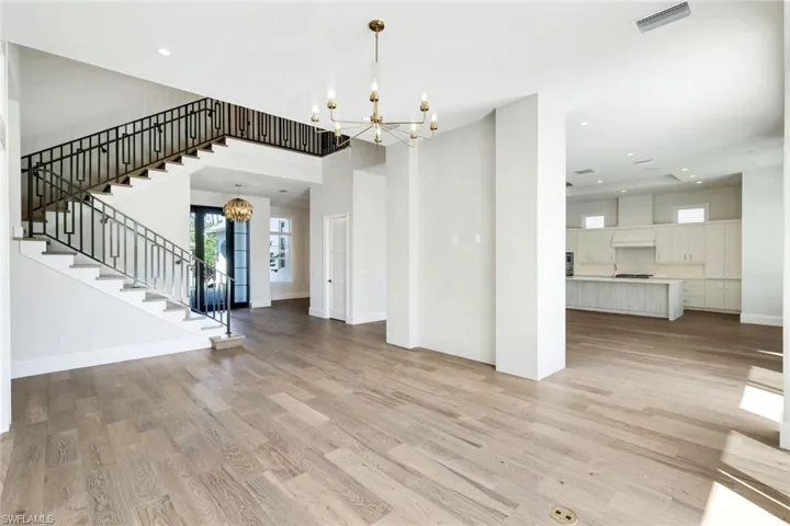 Unfurnished living room with suspended lighting and light wood-type flooring