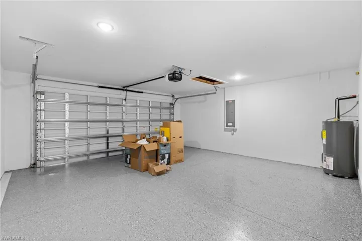 Garage featuring water heater, electric panel, and a garage door opener