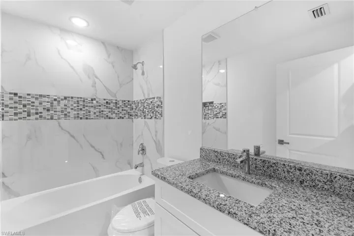 Bathroom featuring toilet, vanity, and bathing tub / shower combination