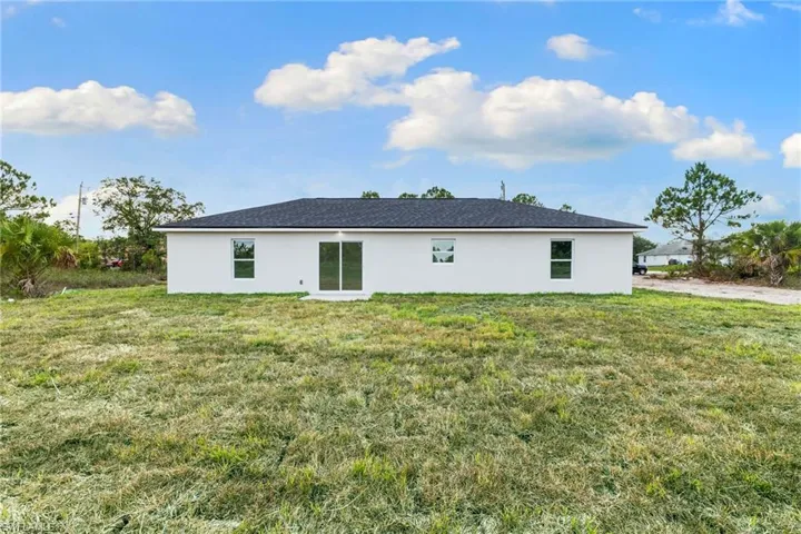 Back of house with stucco siding and a yard