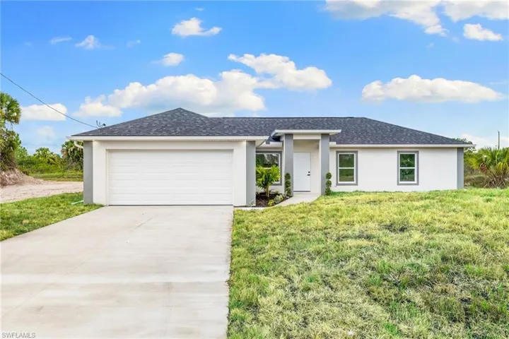 View of front of property with stucco siding, a front lawn, driveway, a garage, and roof with shingles