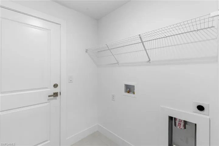 Washroom featuring hookup for an electric dryer, hookup for a washing machine, baseboards, and light tile patterned floors