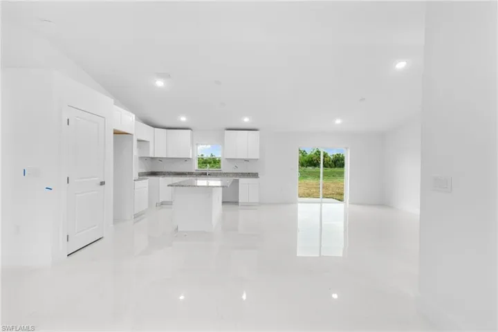 Kitchen with open floor plan, a center island, light marble finish floors, white cabinets, and recessed lighting