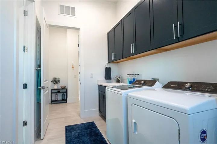 Laundry area featuring visible vents, a sink, washer and clothes dryer, light wood-style floors, and cabinet space