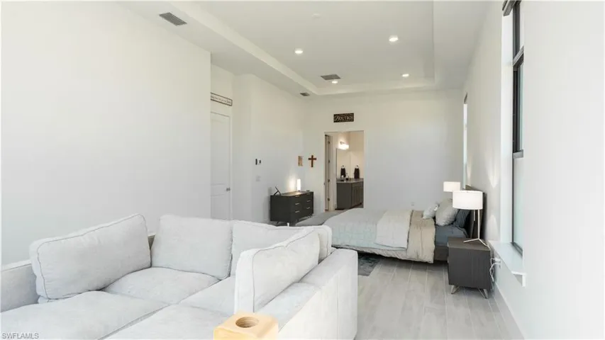 Bedroom with recessed lighting, ensuite bathroom, a tray ceiling, and visible vents