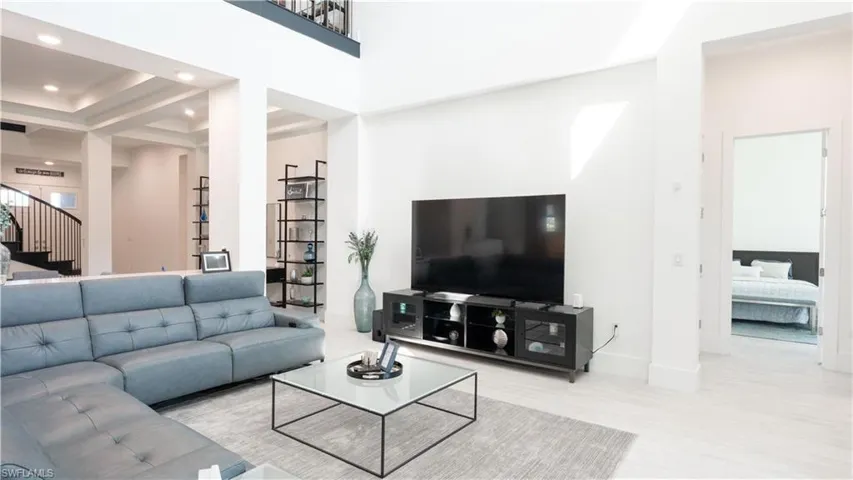 Living area with stairway, baseboards, a high ceiling, and recessed lighting