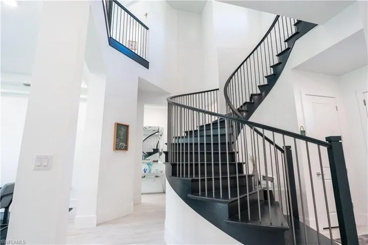 Stairway with baseboards, a high ceiling, and wood finished floors