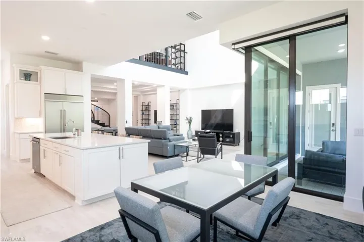 Dining room with stairs, a towering ceiling, light wood-type flooring, visible vents, and recessed lighting