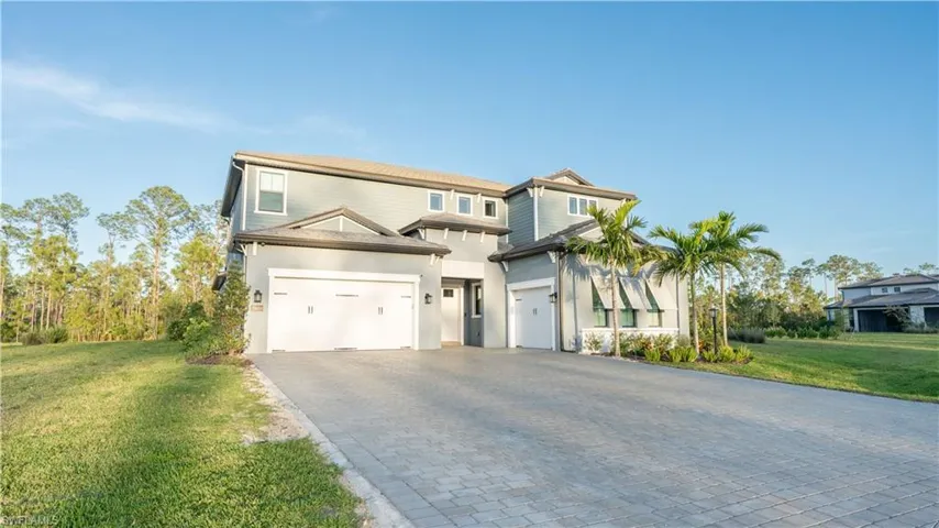View of front of property with an attached garage, decorative driveway, stucco siding, and a front lawn