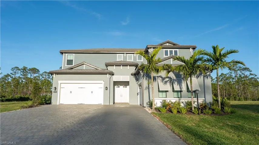 View of front of home featuring an attached garage, stucco siding, decorative driveway, and a front yard