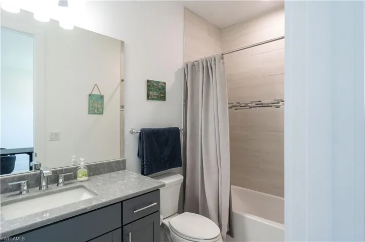 Bathroom featuring vanity, toilet, and shower / bath combination with curtain
