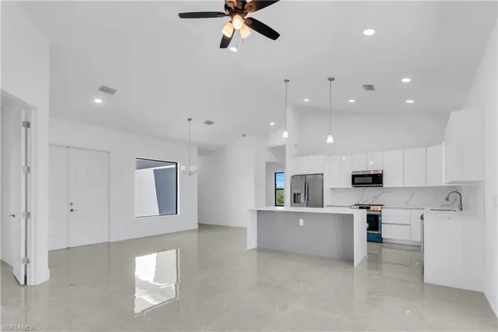 Kitchen featuring white cabinets, appliances with stainless steel finishes, a kitchen island, and hanging light fixtures