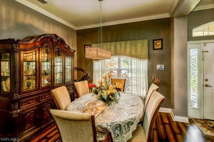 Dining area featuring dark wood-style flooring and crown molding