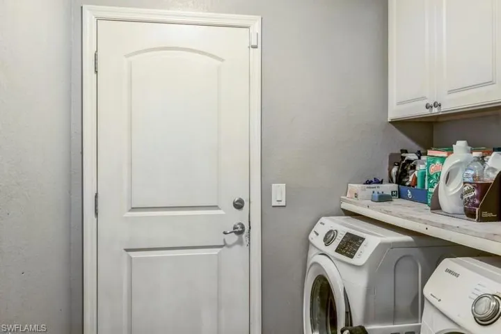Laundry room featuring a textured wall, cabinet space, and washer and dryer