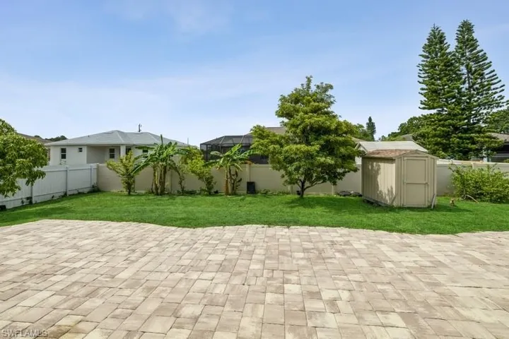 Fenced backyard featuring a shed