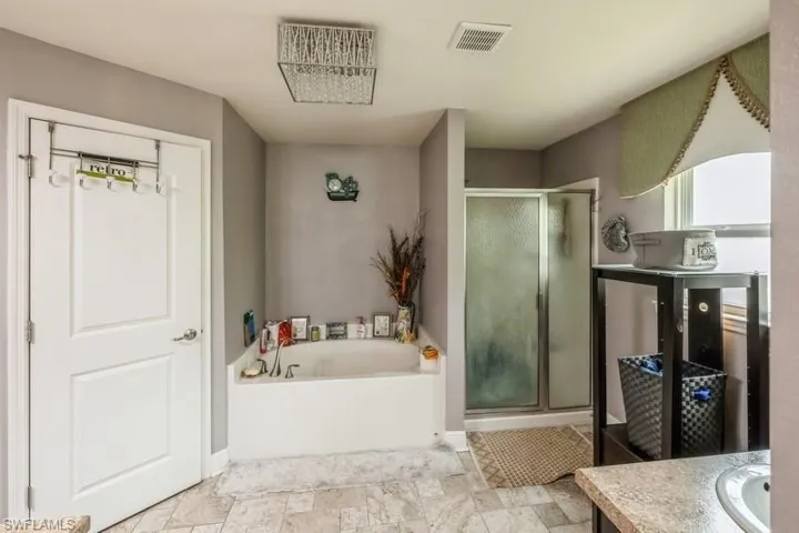 Full bath with vanity, a stall shower, and a garden tub