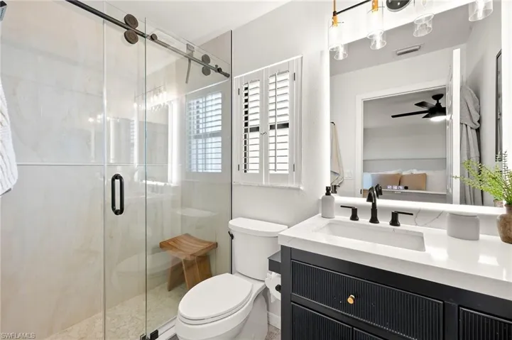 Ensuite bathroom with vanity, a stall shower, and ceiling fan