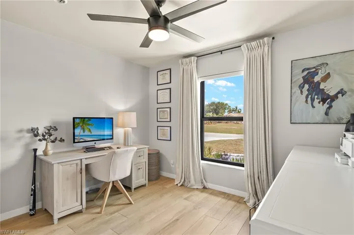 Home office with light wood-type flooring and a ceiling fan