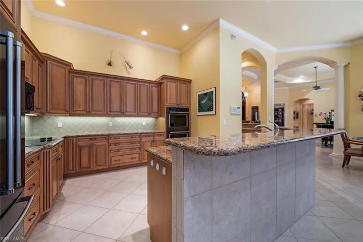 Kitchen with ample cabinet space,  kitchen island with sink, and crown molding