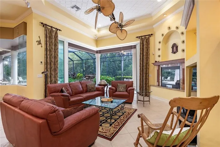 Tiled great room featuring crown molding, plenty of natural light, and ceiling fan and gas fireplace