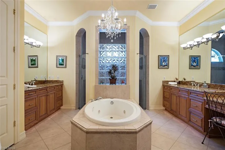 Primary bedroom en-suite featuring dual vanities, crown molding, and independent shower and bath