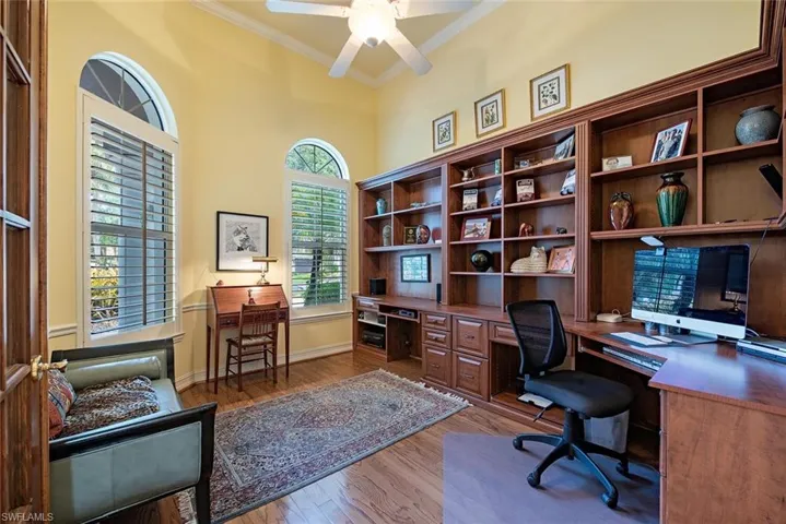 Office space with built in cabinets, crown molding, hardwood / wood floors, and ceiling fan
