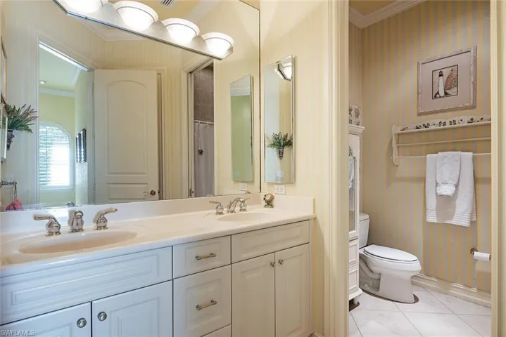 Guest bathroom with crown molding, vanity, toilet, and tile patterned flooring