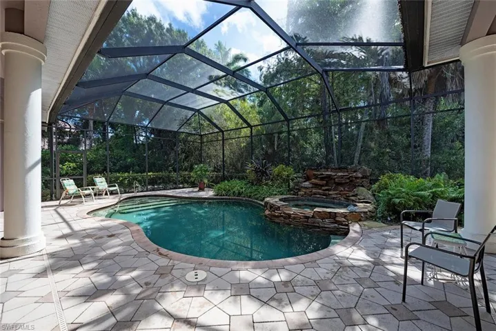 View of swimming pool with screened lanai enclosure, an in ground hot tub, and a patio